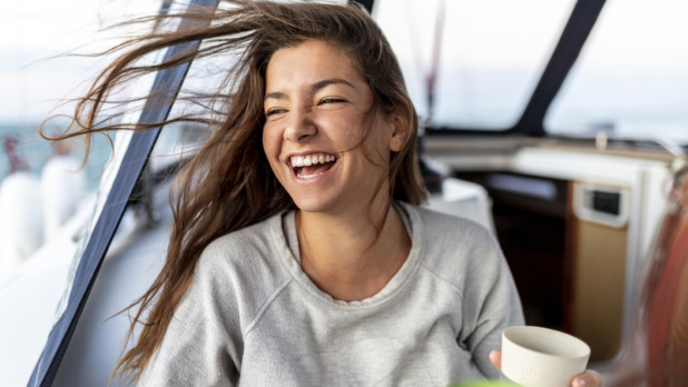 happy and young woman on a sail boot drinking hot tea in the morning