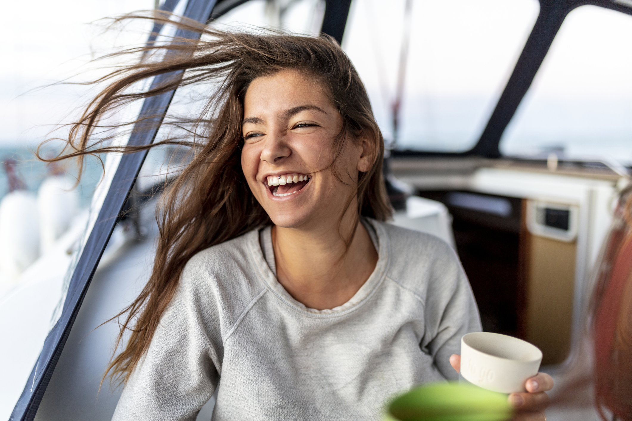 happy and young woman on a sail boot drinking hot tea in the morning