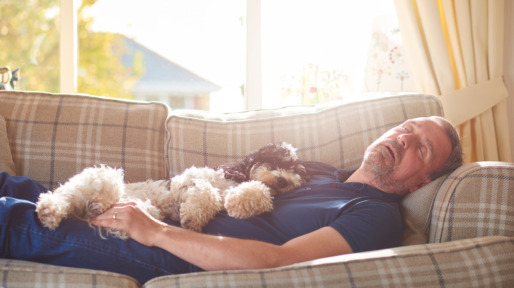 Man slaapt overdag op de bank samen met zijn hondje