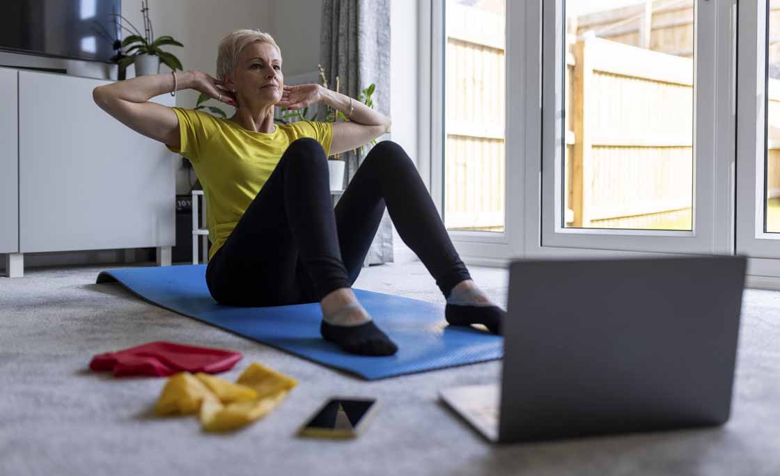 Determined woman doing crunches while e-learning through online tutorial at home