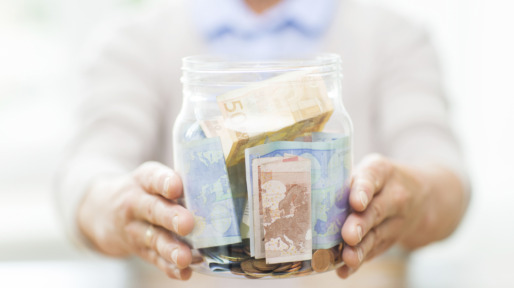 close up of senior woman with money in glass jar