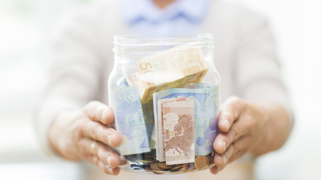 close up of senior woman with money in glass jar