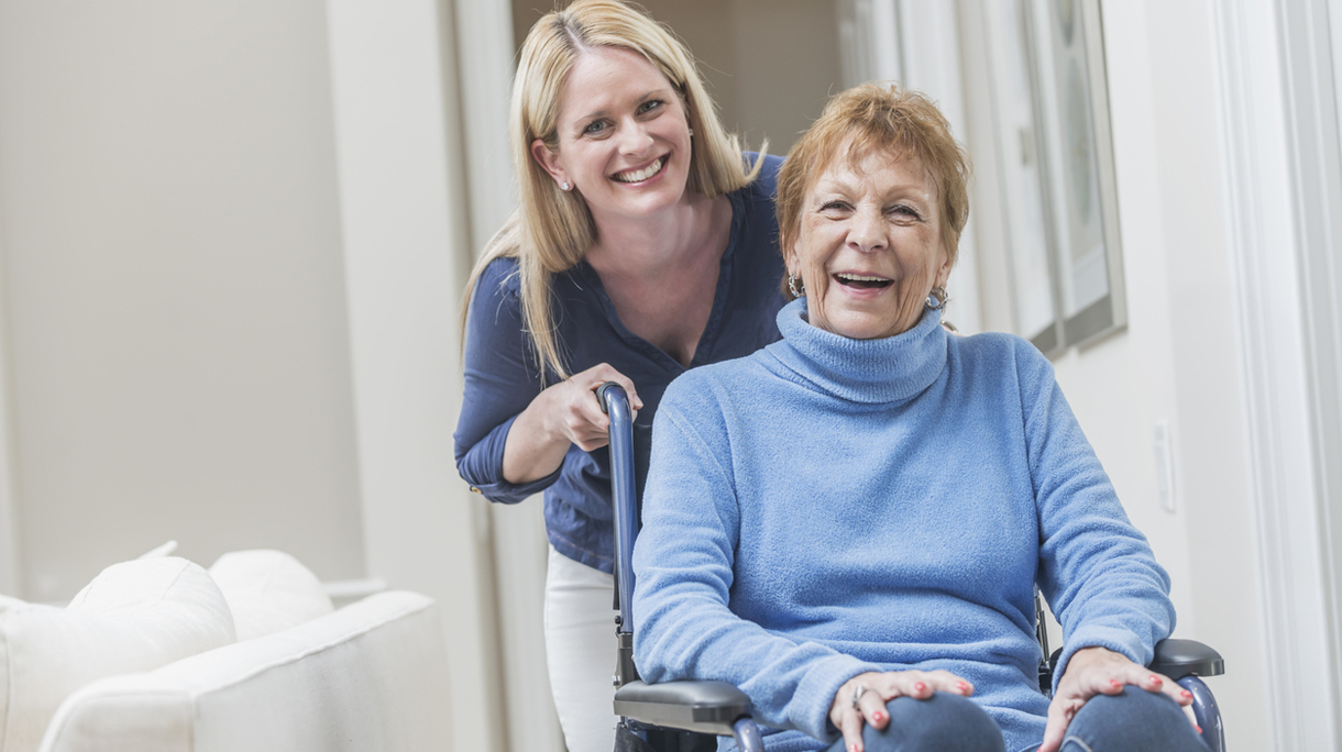 Senior woman in wheelchair with caregiver at home