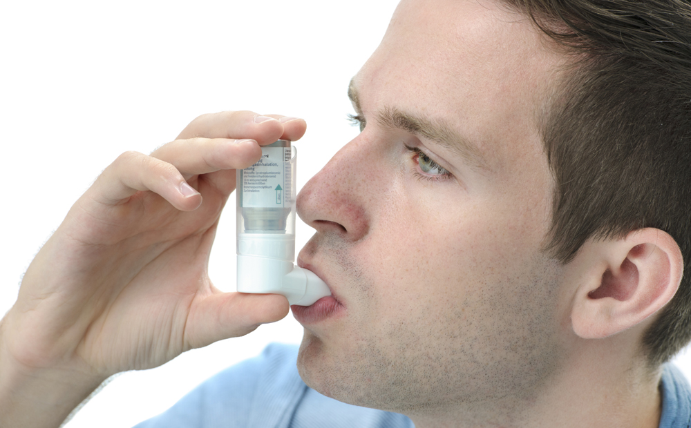 Young man using an asthma inhaler
