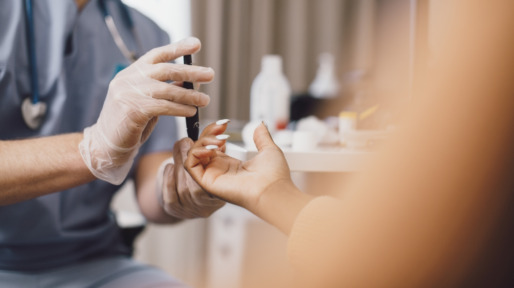 Midsection of male doctor measuring blood sugar through glaucometer in clinic