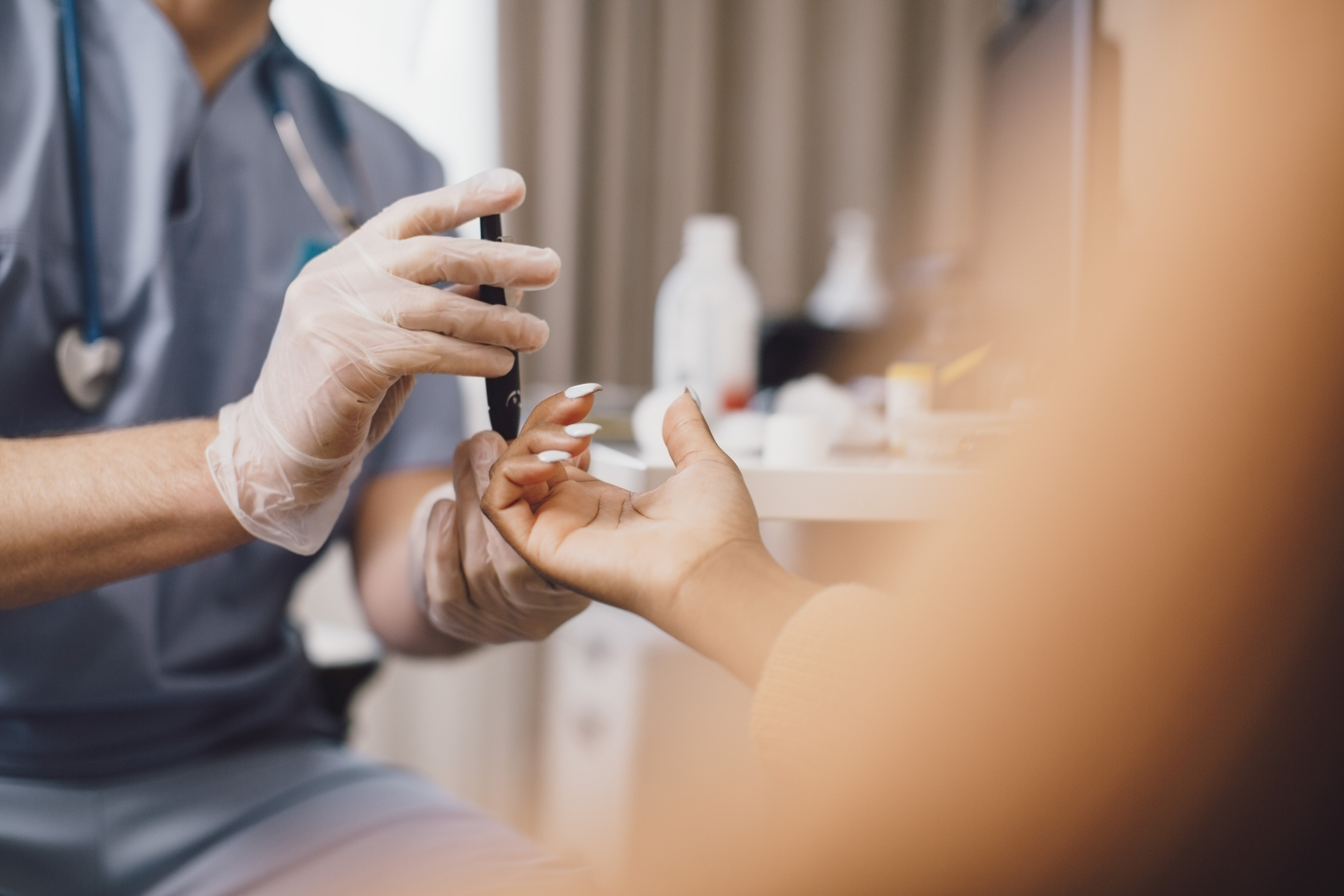 Midsection of male doctor measuring blood sugar through glaucometer in clinic