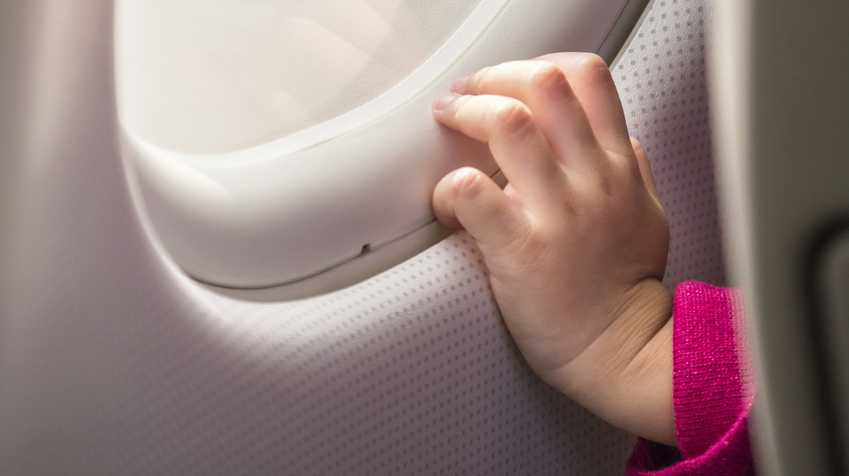 Child’s hand touching airplane window