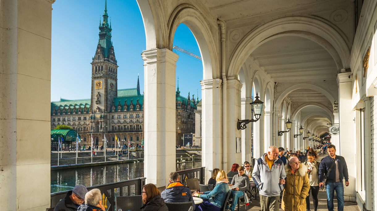 Hamburg crowds enjoying Alsterarkaden restaurants overlooked by Rathaus tower Germany