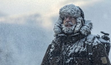 Man with furry  in snowstorm with cloudy skies and snowflakes