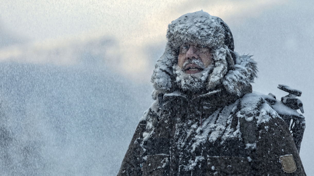 Man with furry  in snowstorm with cloudy skies and snowflakes