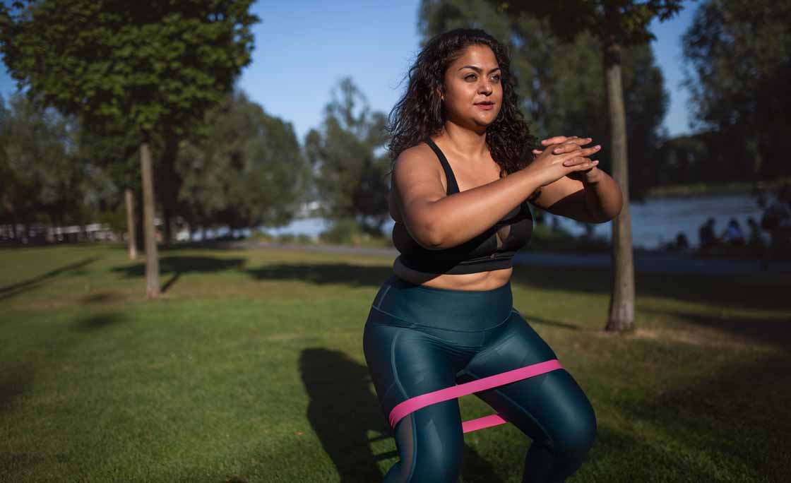 Portrait of beautiful young overweight woman outdoors on riverbank in city,  doing exercise.