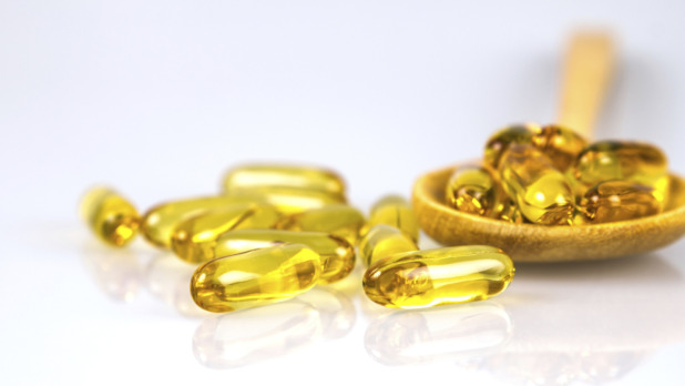 Closeup yellow soft gelatin supplement fish oil capsule