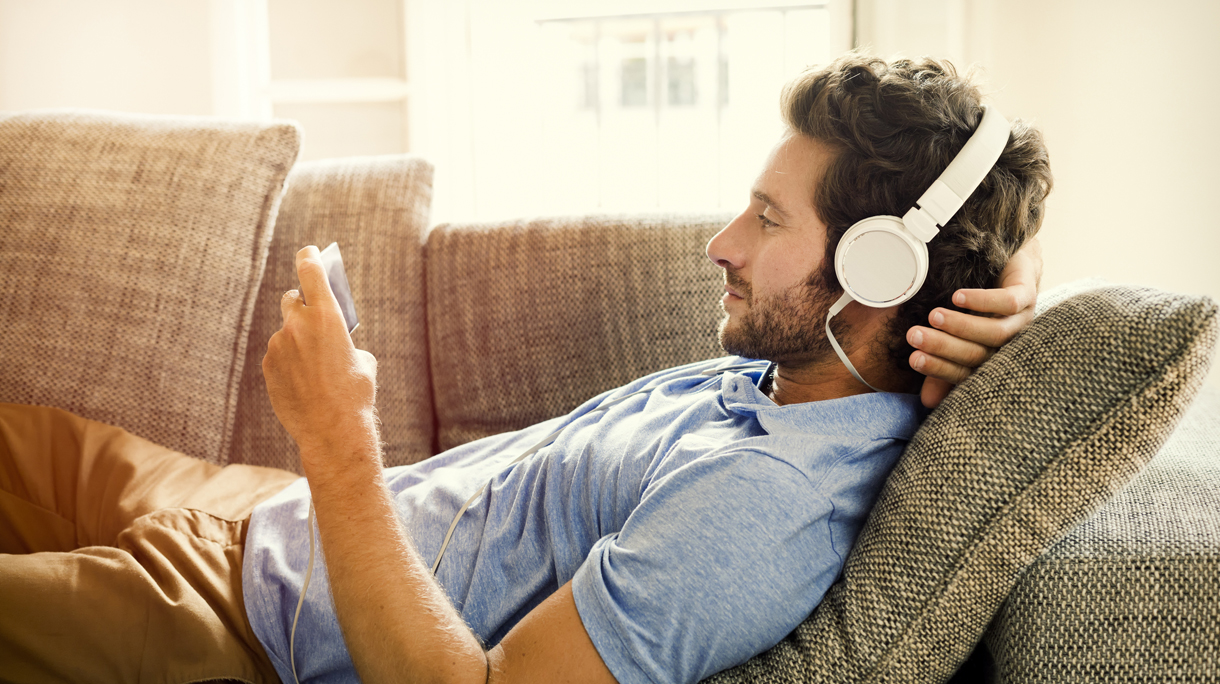 Man on couch watches a movie on mobile phone