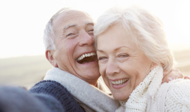 Senior Couple Standing On Beach Taking Selfie