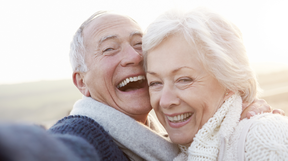 Senior Couple Standing On Beach Taking Selfie
