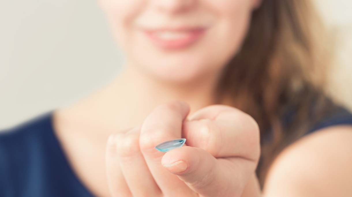 Woman inserting a contact lens in eye.