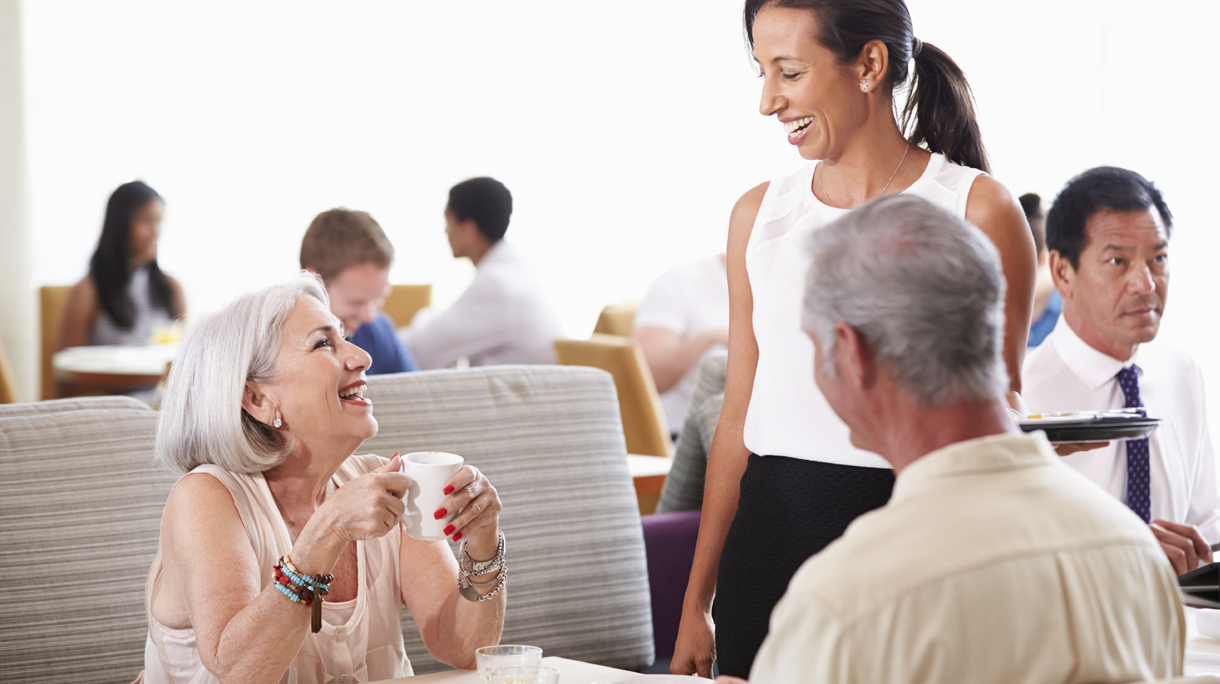 Waitress Serving Senior Couple Breakfast In Hotel Restaurant