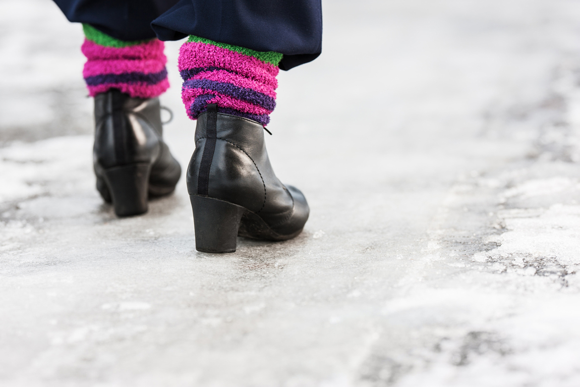 Woman wearing black boots with heels walking on ice