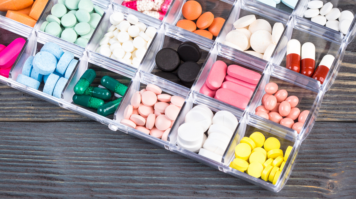Pills in plastic container on gray tabletop
