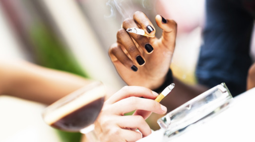 Human hands of two different ethnicity woman holding cigarettes