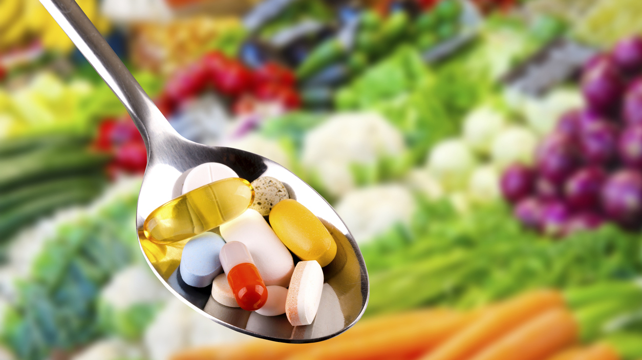 spoon with pills, dietary supplements on vegetables background