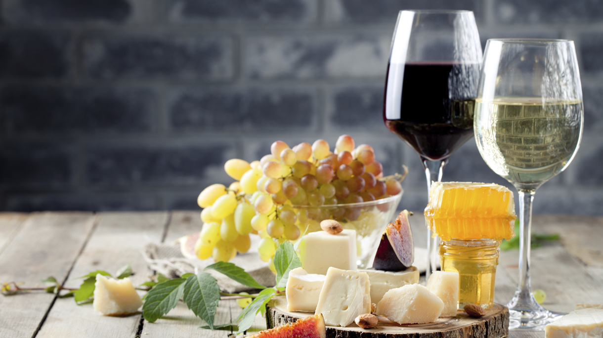 Grape, cheese, figs and honey with a glasses wine.