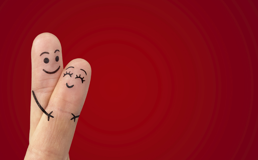 A happy couple in love with painted smiley and hugging