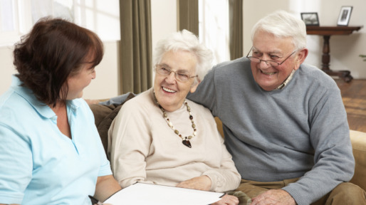 Senior Couple In Discussion With Health Visitor At Home