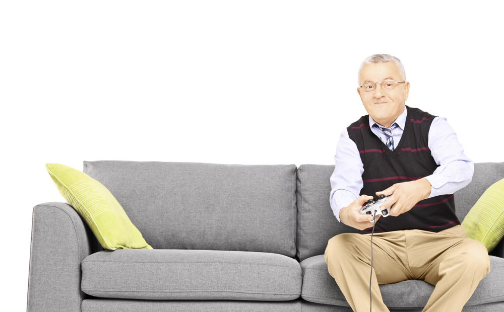 Senior man sitting on a couch and playing video games