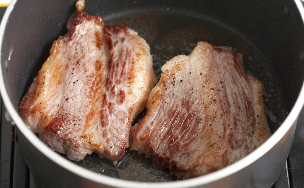 cooking beef in black pan in kitchen