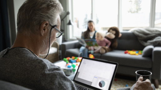 Senior man using laptop and drinking coffee in living room