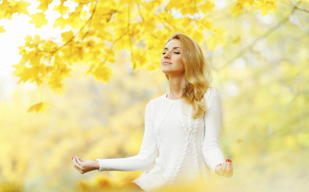 Woman meditating in autumn park