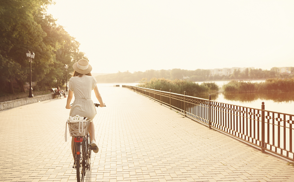 Girl riding a bicycle in park near the lake. Lightleak effect an