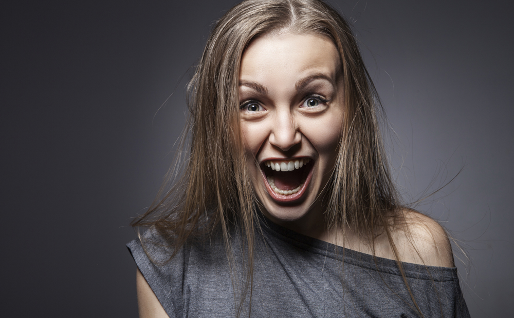 Angry woman screaming over dark grey