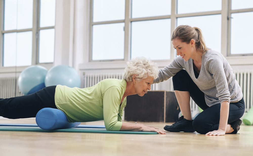 Physical therapist helping elderly woman in her workout