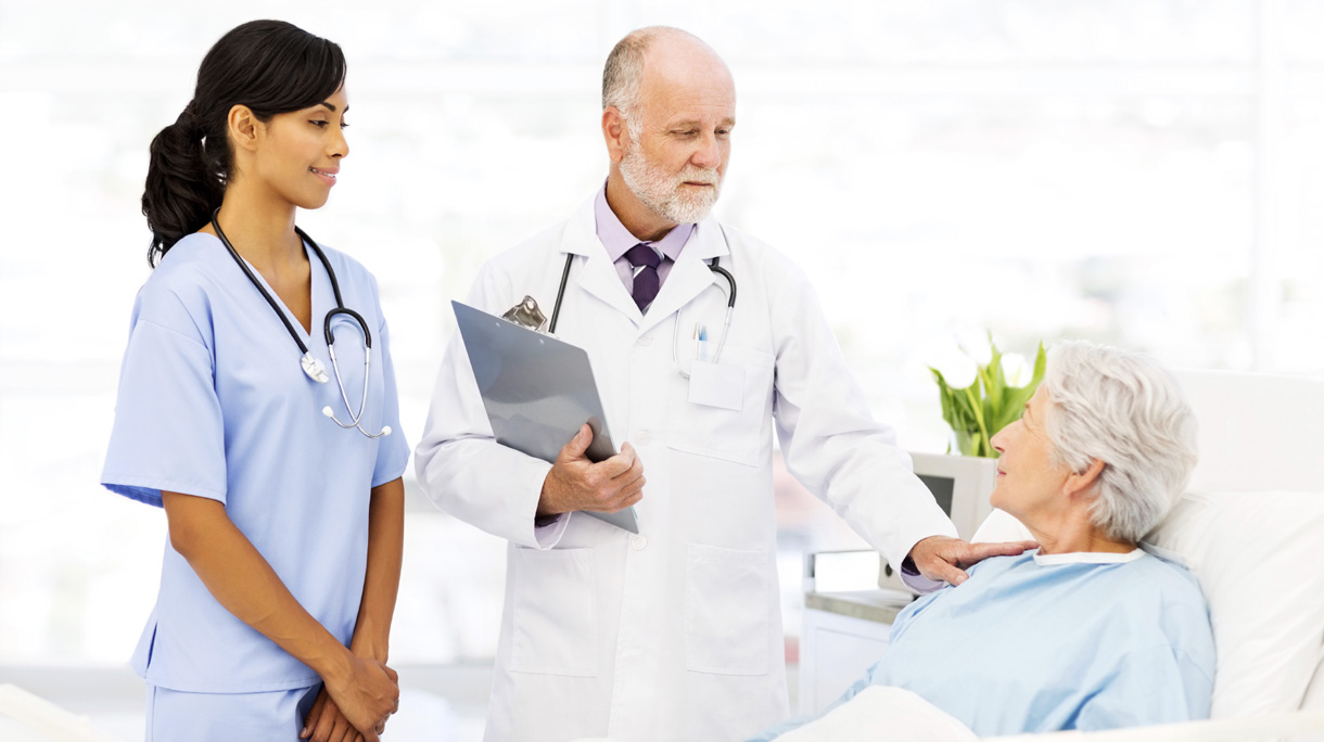 Doctor Consoling Senior Female Patient In Hospital Ward