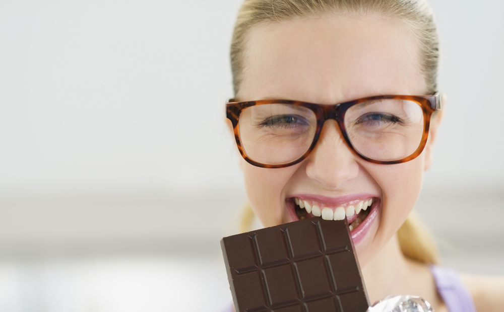 Happy teenage girl eating chocolate bar