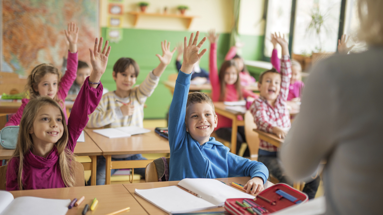 School children raising their hands ready to answer the question.