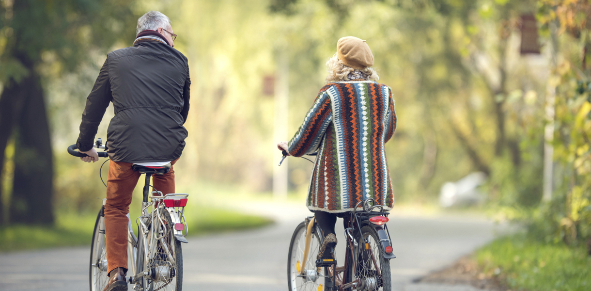 Rear view of mature couple cycling in autumn day.