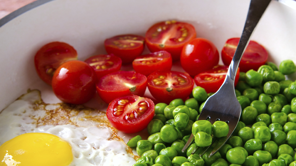 Breakfast with fried egg, green peas and cherry tomatoes