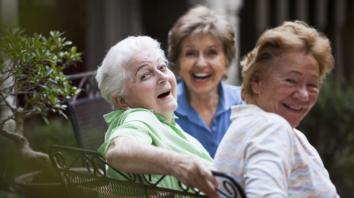 Three elderly women laughing on patio
