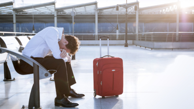 Depressed traveler waiting at airport after flights delays and c