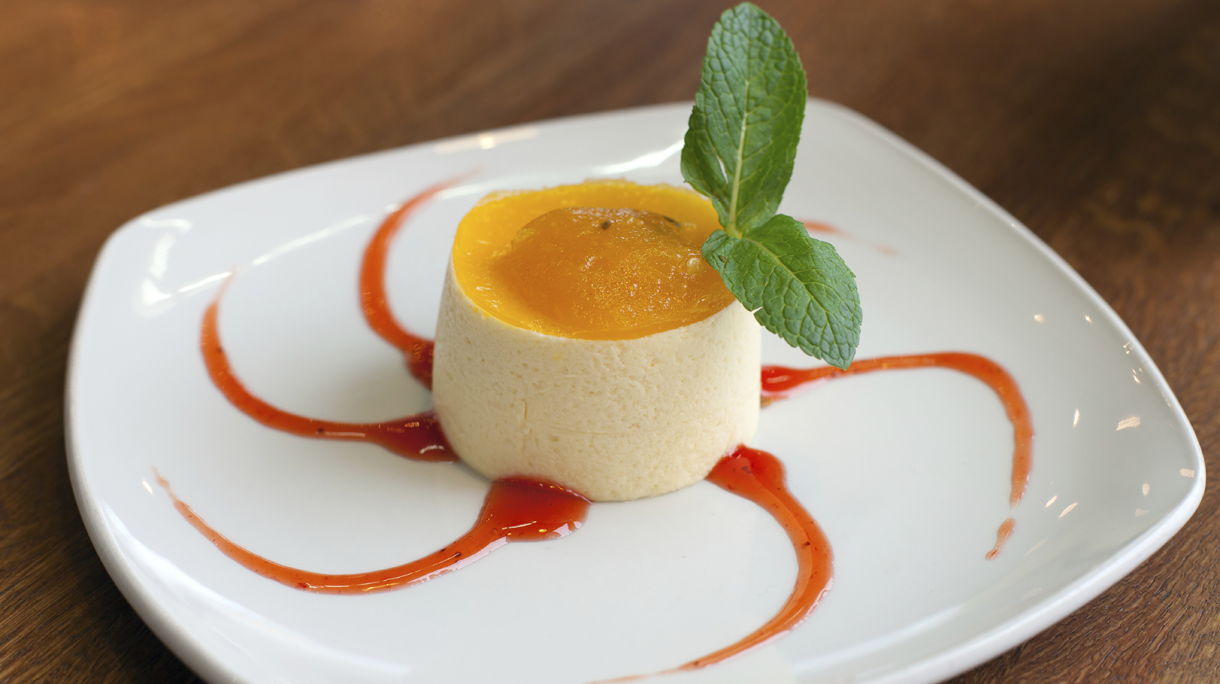 A mousse with passionfruit jam with red syrup on white plate