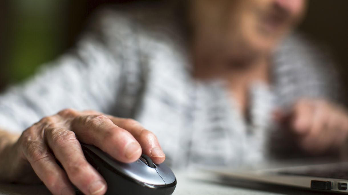Closeup of the hand of an old woman holding a computer mouse.