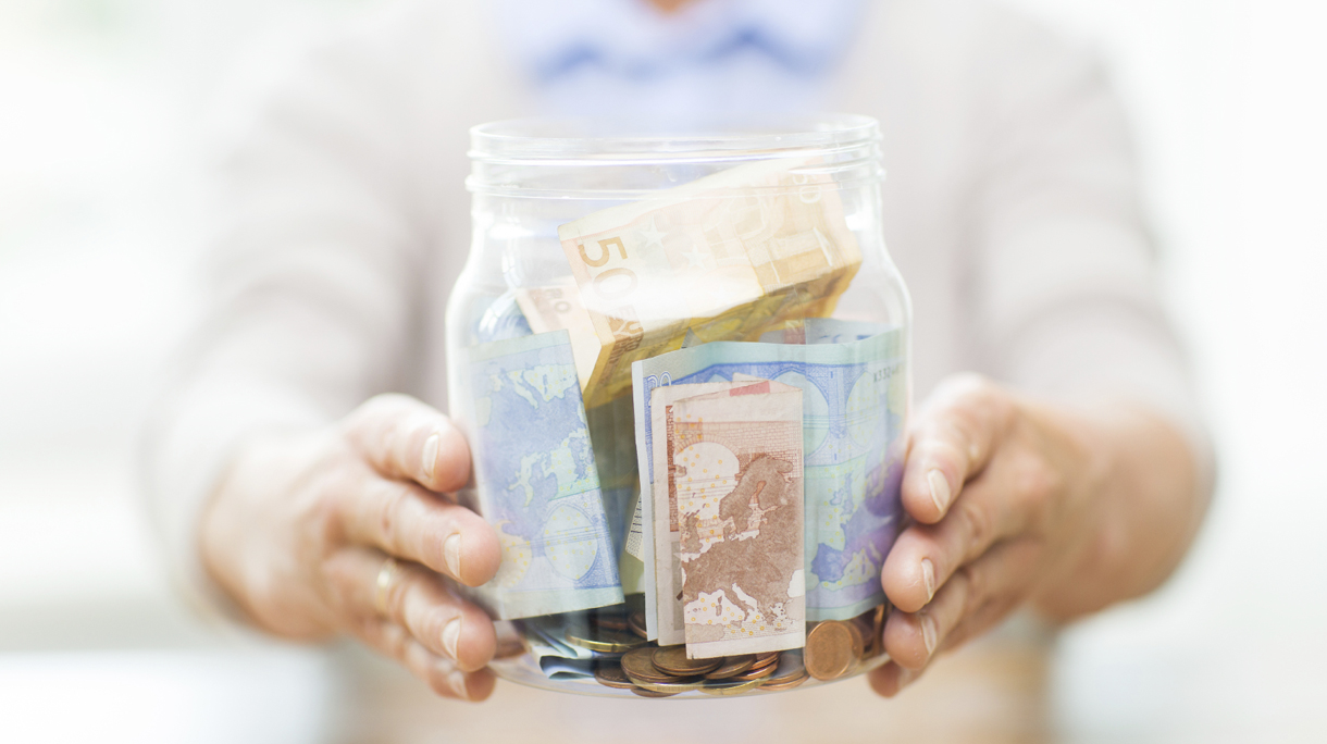 close up of senior woman with money in glass jar