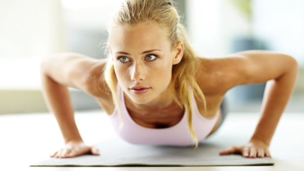 Attractive young lady doing push ups on exercise mat