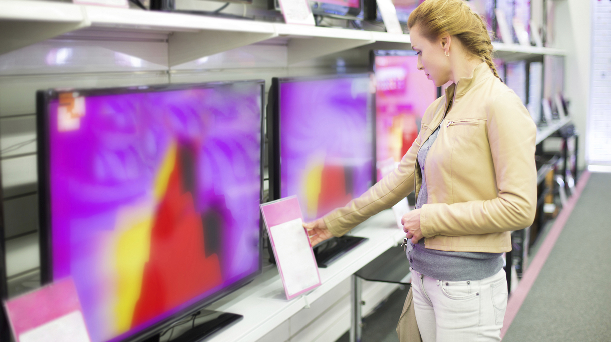 A woman observing prices for a television in a store