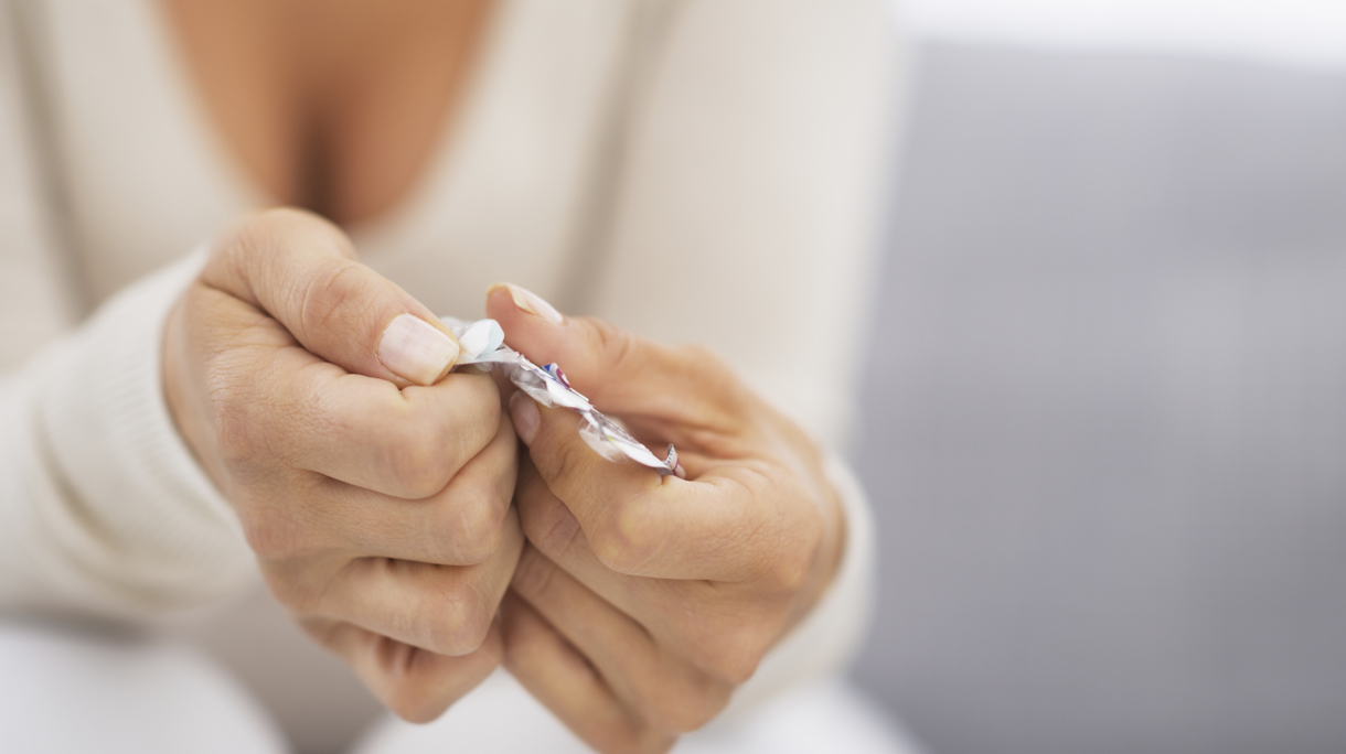 Closeup on hand pushing pill out of blister package