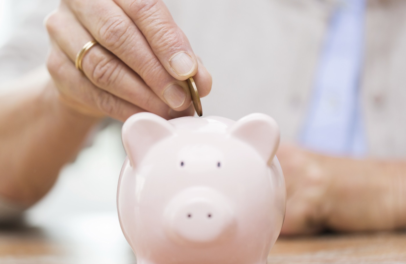 senior woman hand putting money to piggy bank