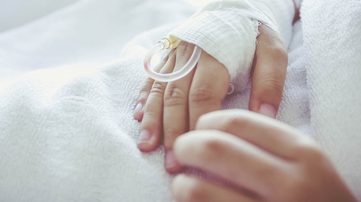 Saline intravenous (iv) drip in a child’s patient hand. Vintage